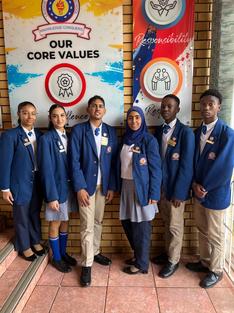 Student leaders in front of the school's Our Core Values wall display